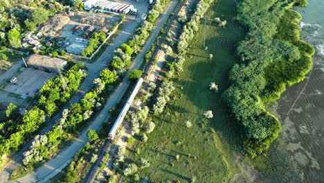 aerial tracking shot of moving train next to a lake in daytime