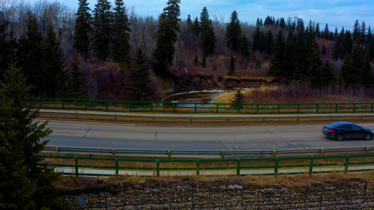 방과 후 아이들이 하차한 후 보도 경로에 녹색 나무 울타리가 있는 숲이 있는 녹은 눈둑 강이 내려다보이는 돌다리를 건너는 학생들로 가득 찬 학교 버스