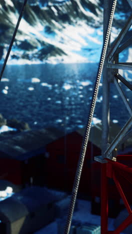 a close up shot of a red metal structure in the snow covered landscape of antarctica