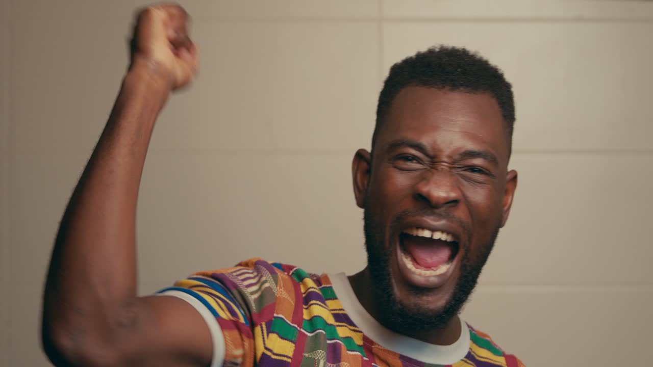 ritratto di un uomo afroamericano che indossa una camicia di tessuto kente che celebra in modo emozionante al rallentatore