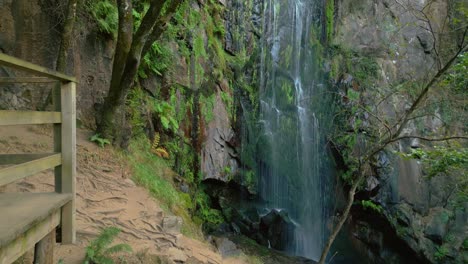 plataforma de observación con cascada de aguacaida que fluye hacia abajo en el acantilado de musgo dentro del bosque