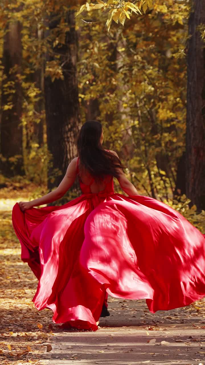 A Woman Elegantly Twirls in a Flowing Red Dress Amidst a Serene Autumn Forest, Capturing the Beauty of Nature and Fashion in Perfect Harmony