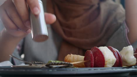 woman eating skewers with cheese and sausages