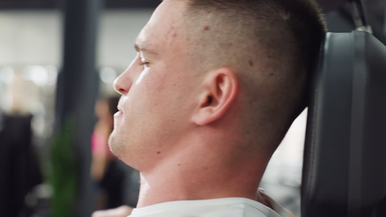 Close up side view of gym goer grasping elliptical handles straining face in intense cardio workout sweat dripping muscles flexing powering through movement endurance training session