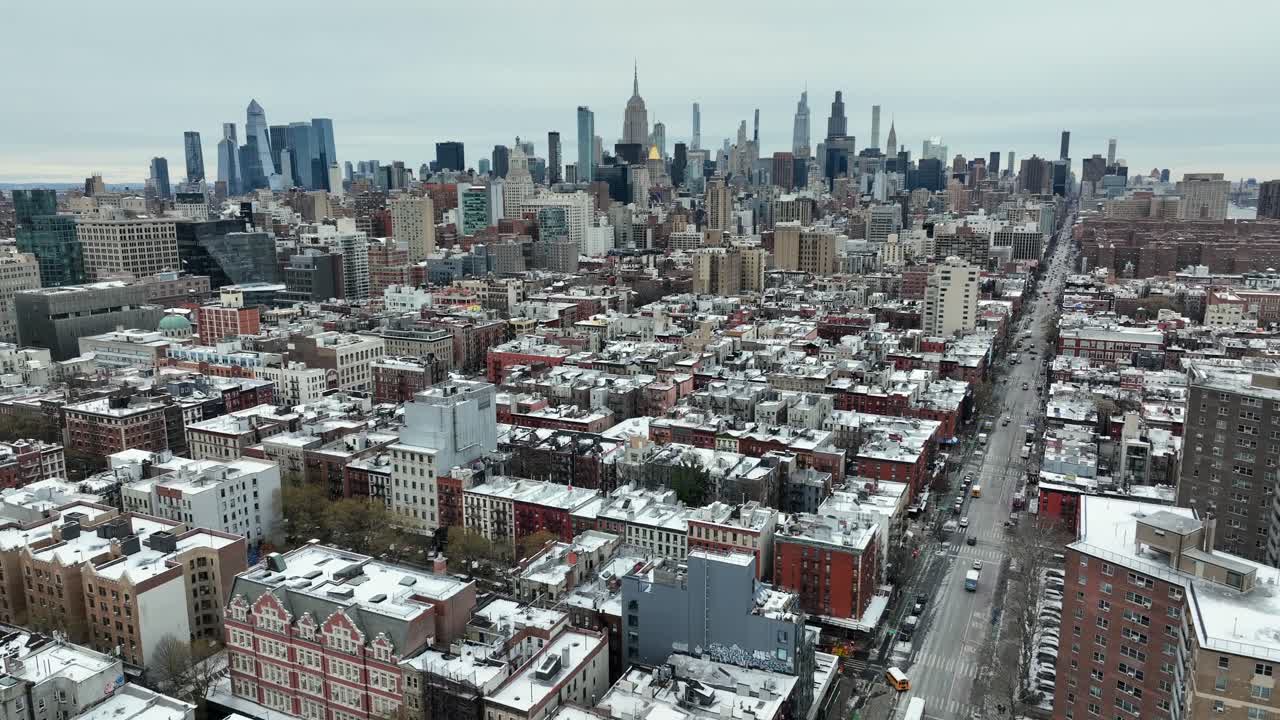 New York City viser sneklædte hustage, tætte boligkvarterer og trafik langs en bred urban gade under en kold, overskyet himmel. Gule skolebusser på gaden. Aerial Rising wide shot