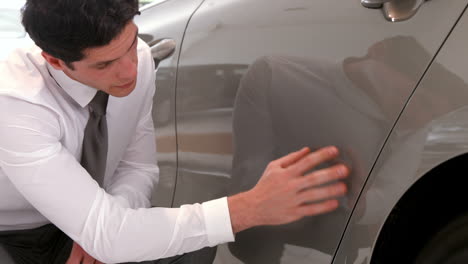 un hombre de negocios comprobando la pintura de los coches.