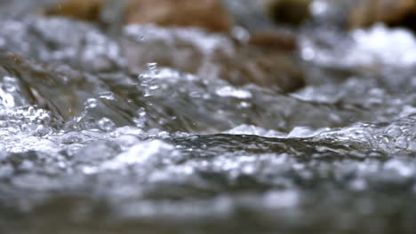 Clear-stream-running-through-stone-boulders-Abundant-river-flowing-in-slow-motion