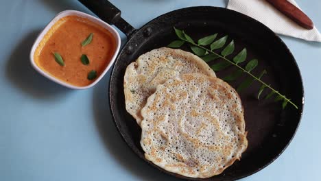 Conjunto-Giratorio-Dosa-Es-Un-&#39;conjunto&#39;-De-2-Dosas-Cubiertas-Con-Mantequilla-O-Ghee-Y-Chutney-Sobre-Fondo-Azul