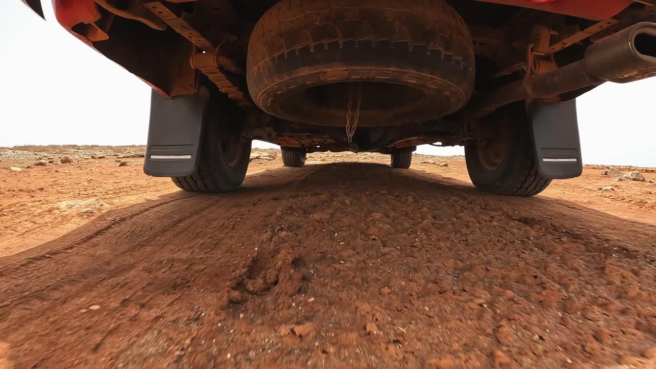 Driving on vast arid desert dirt road of Boa Vista island, Cape Verde. Under the car point of view