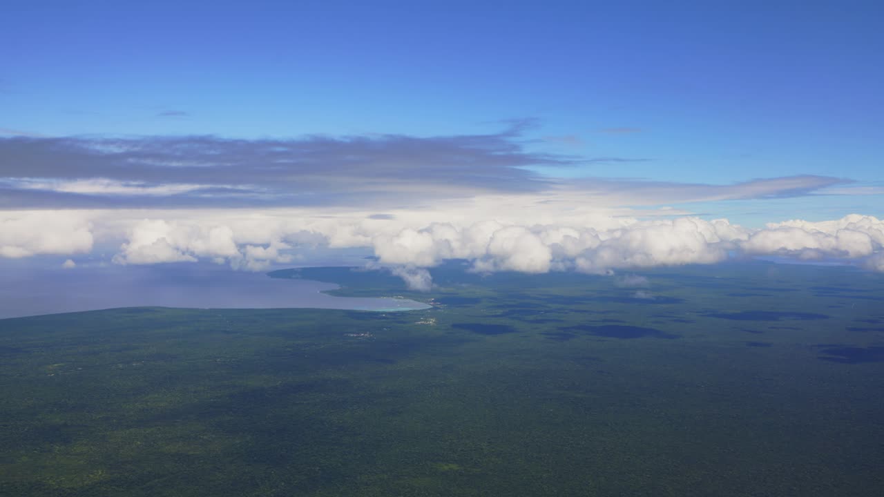 una vista desde un avión revela una isla de bosque tropical exuberante rodeada de nubes blancas
