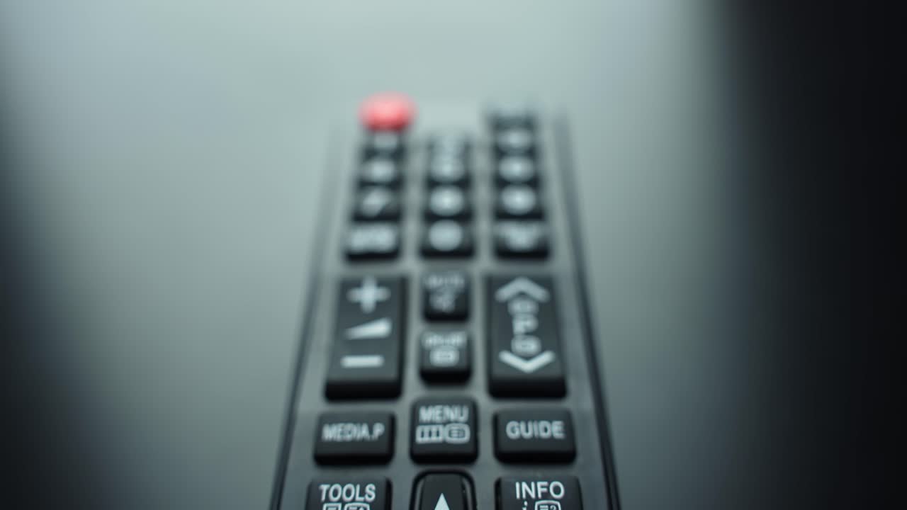 Macro close-up of TV remote numeric keypad with power button, shallow depth of field and copy space. Concept for streaming, channel surfing, home entertainment UI