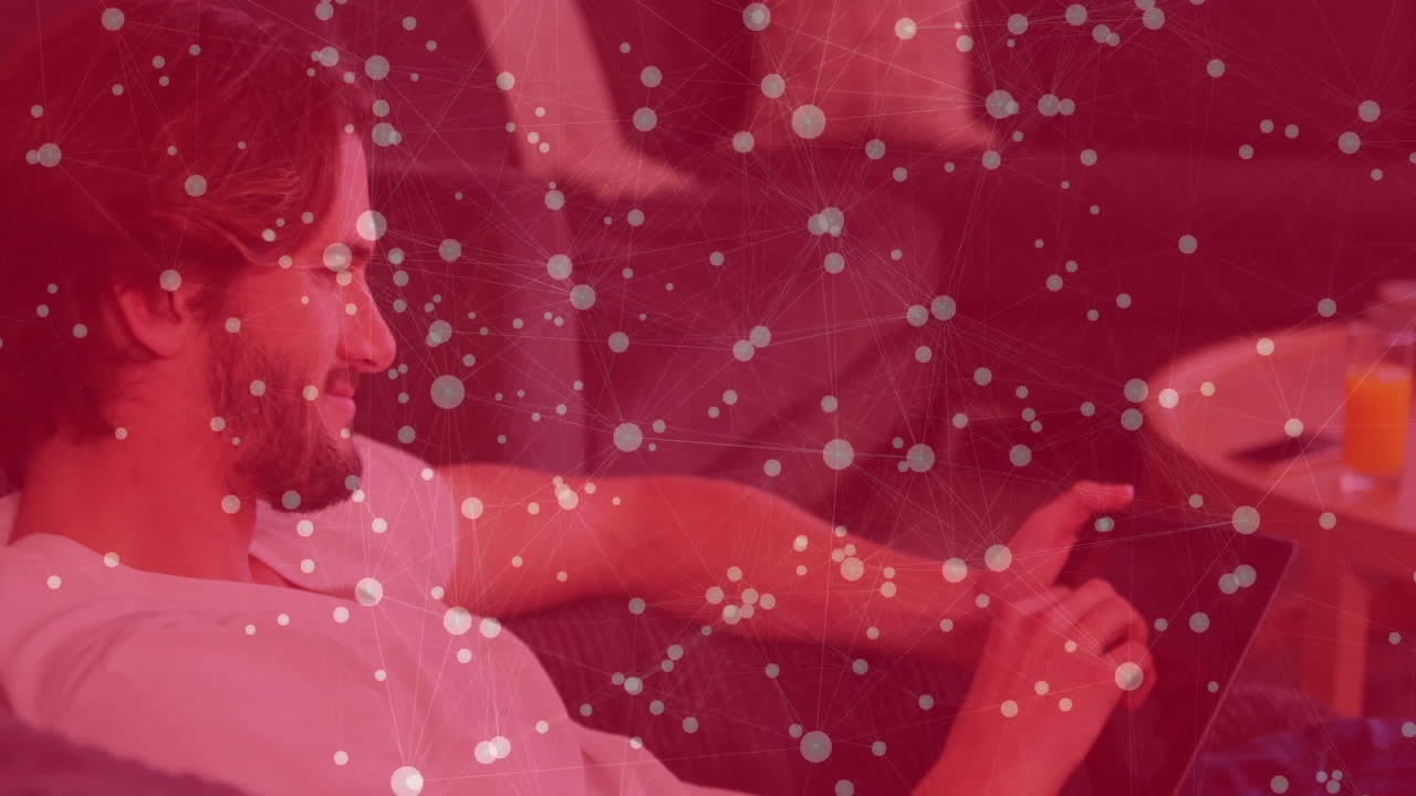 Man reclining on sofa interacting with tablet in technology context, showing data network overlay