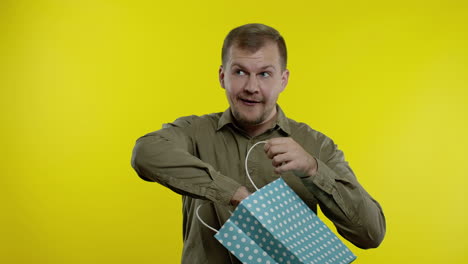 man showing black friday inscription from shopping bag, smiling, rejoicing discounts, low prices