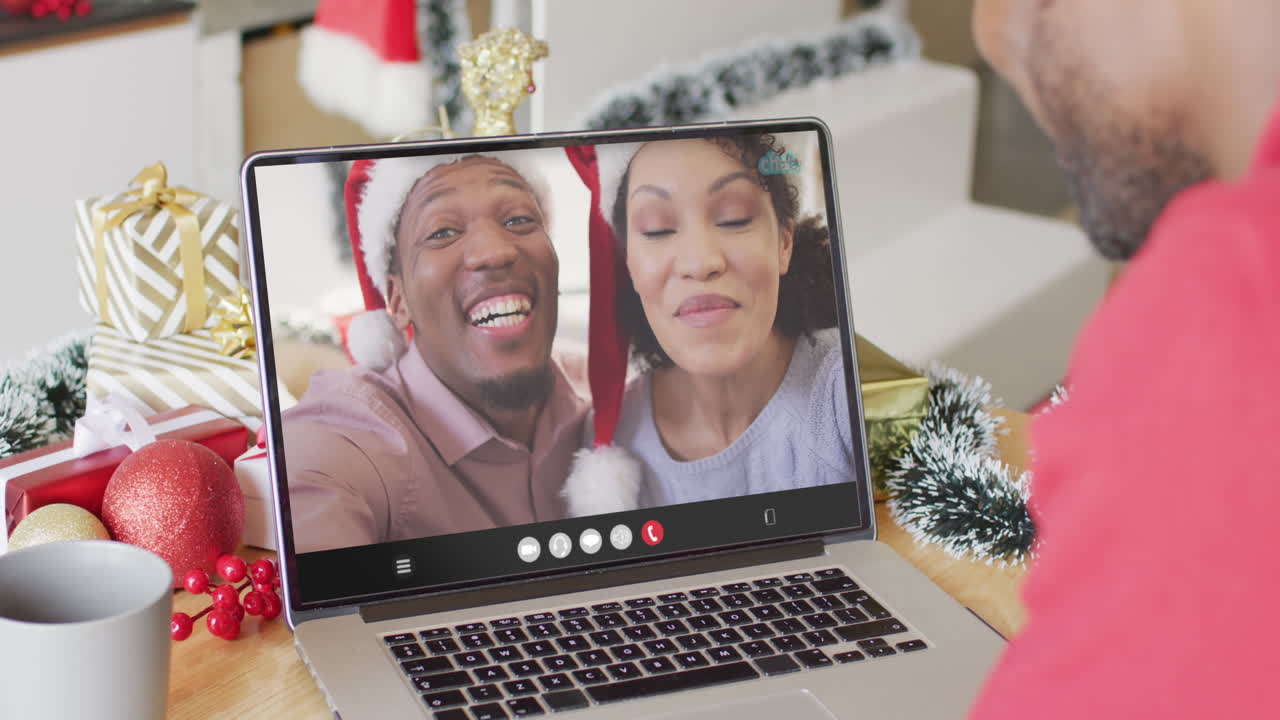 hombre afroamericano con decoraciones de navidad teniendo una llamada de video con una pareja diversa