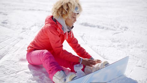 Skier-attaching-a-snowboard-to-her-boots