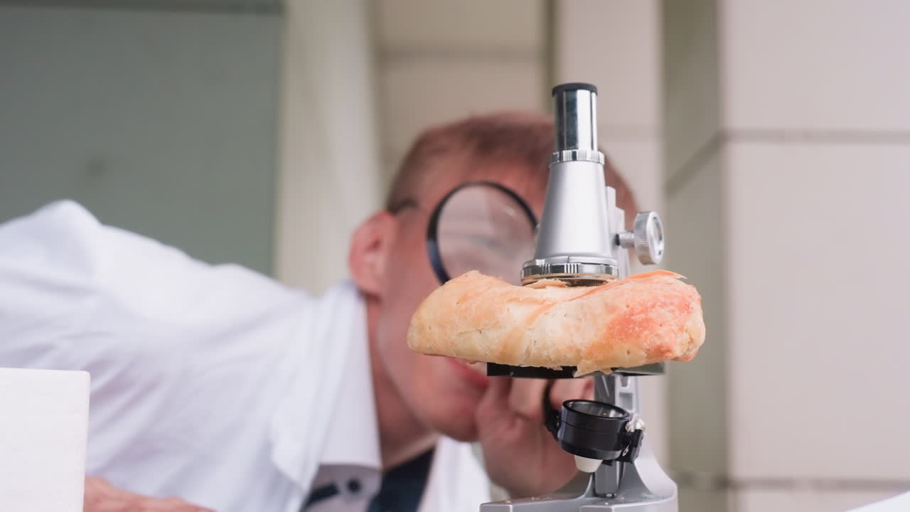 Young scientific researcher in white coat rises up carefully observing pastry with microscope outdoors, reflecting curiosity, focus, and dedication to experimental study with notebook and pen nearby