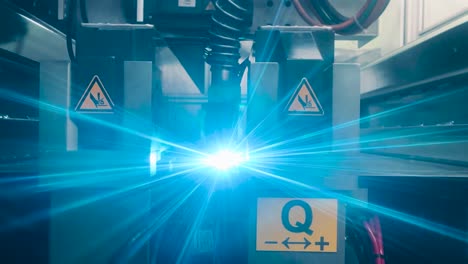 industrial laser machine welding metal, a robotic mechanism in a factory. technology concept. a flat sheet of stainless steel is being welded with flashes. front view. type a