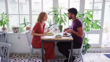 young adult couple talking having lunch together in an empty restaurant, full view