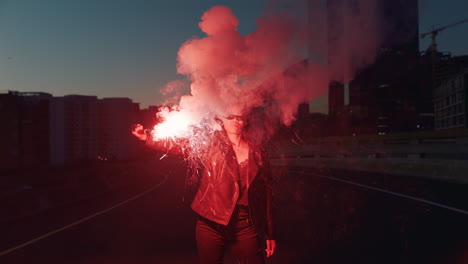 mujer joven agitando una bengala de señal en la ciudad por la noche niña rebelde protestando por la igualdad en la calle con fuegos artificiales movimiento de libertad milenario femenino