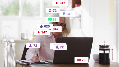 animación de iconos de los medios sobre una mujer caucásica anciana usando una computadora portátil