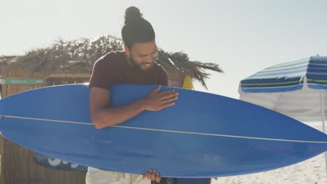 mixed race man holding his surfboard