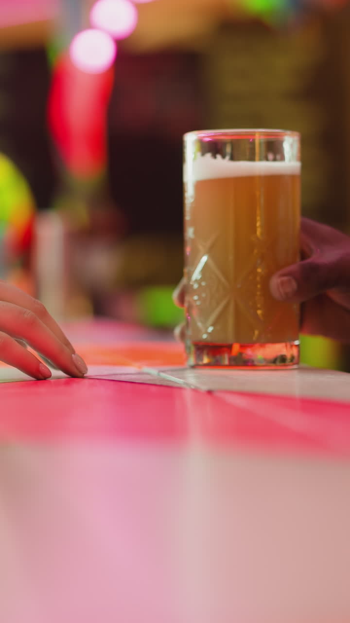 el camarero le da cerveza a la mujer cliente en el mostrador de primer plano. la invitada pide cerveza artesanal al barman negro en un club nocturno. el cliente descansa en un elegante pub