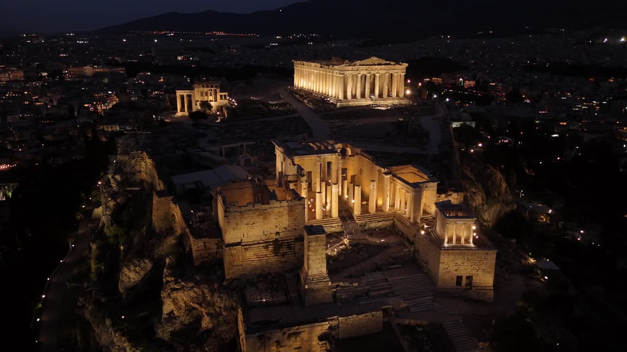 Athens, Aerial view forward towards Beautifully illuminated Acropolis at night. Full view of Panthenon,Erechthenion and entrance of Acropolis in shimmering lights