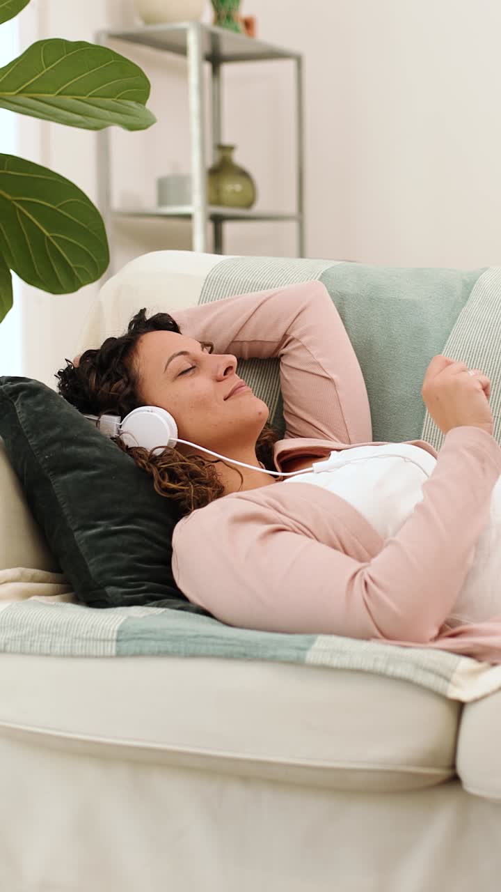 Woman relaxing on sofa listening to music with headphones