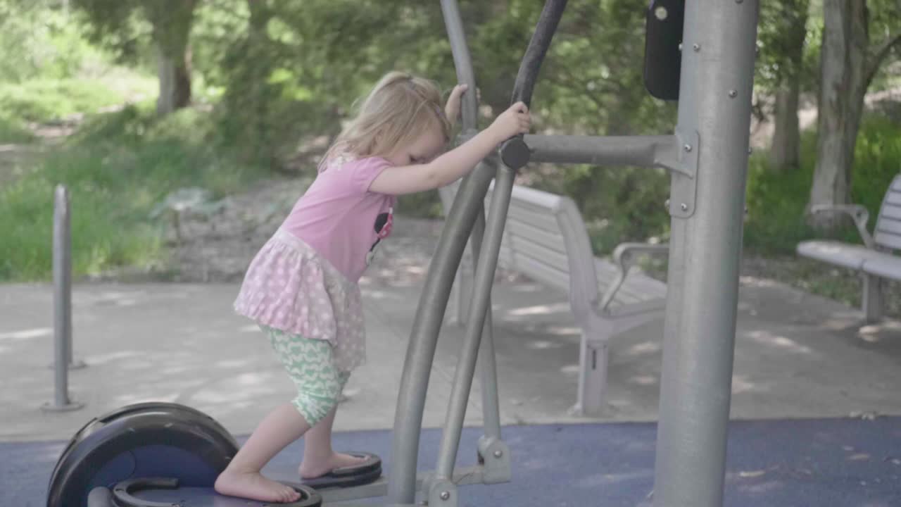 Una bambina gioca su una macchina da palestra per adulti al rallentatore