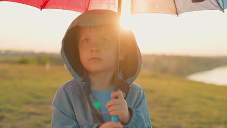 offended boy beneath umbrella shelter child sadness seems to blend with rain becoming