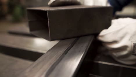 worker in metal factory puts one metal bar on another, close up shot, you can see only his gloves