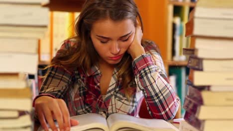 estudiante cansado estudiando en la biblioteca rodeado de libros