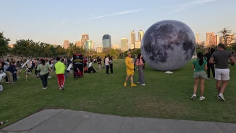 people interacting with a large moon balloon outdoors