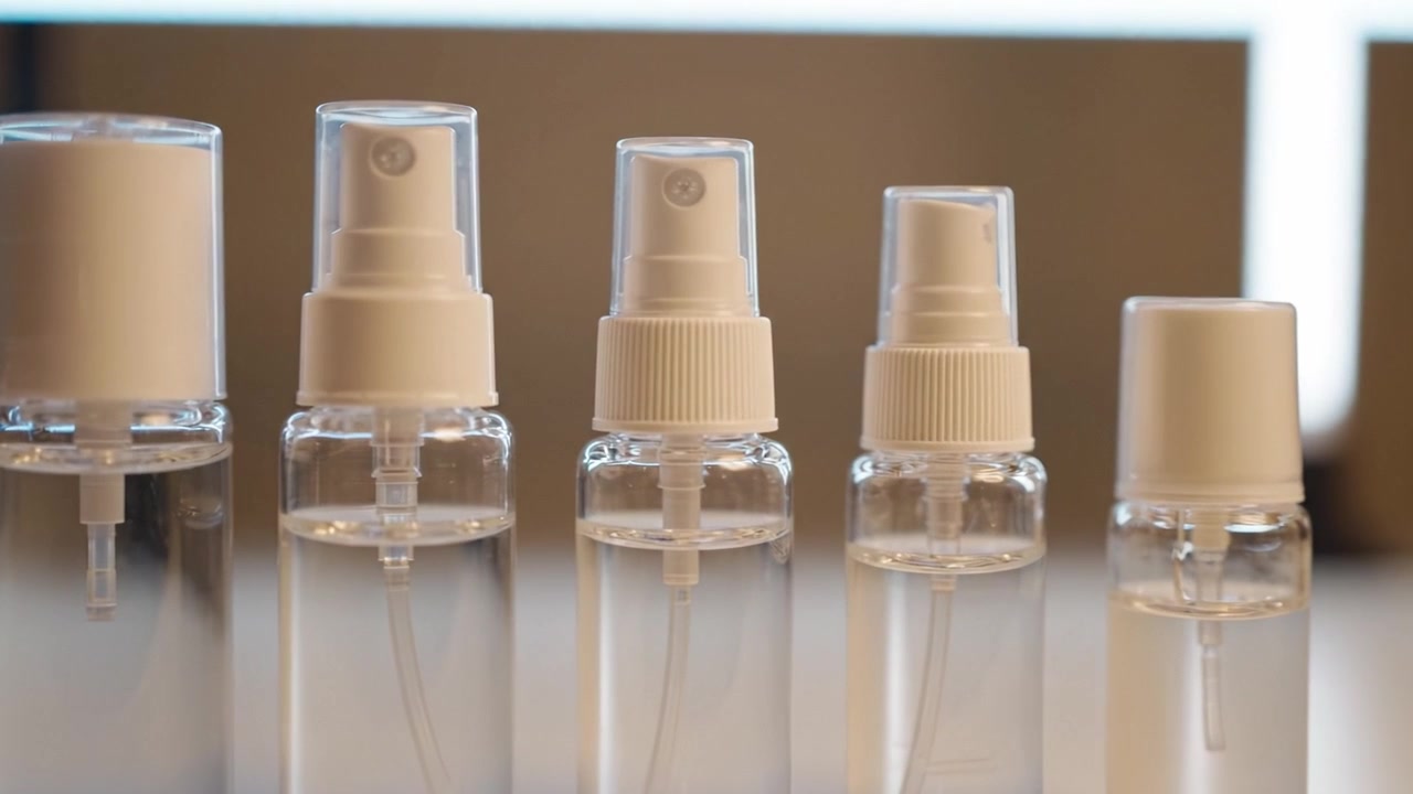 Uma Coleção de Frascos de Spray Transparentes de Vários Tamanhos Exibidos em Ordem, Mostrando Suas Características Distintas e Tampas Contra uma Luz de Fundo Suave.