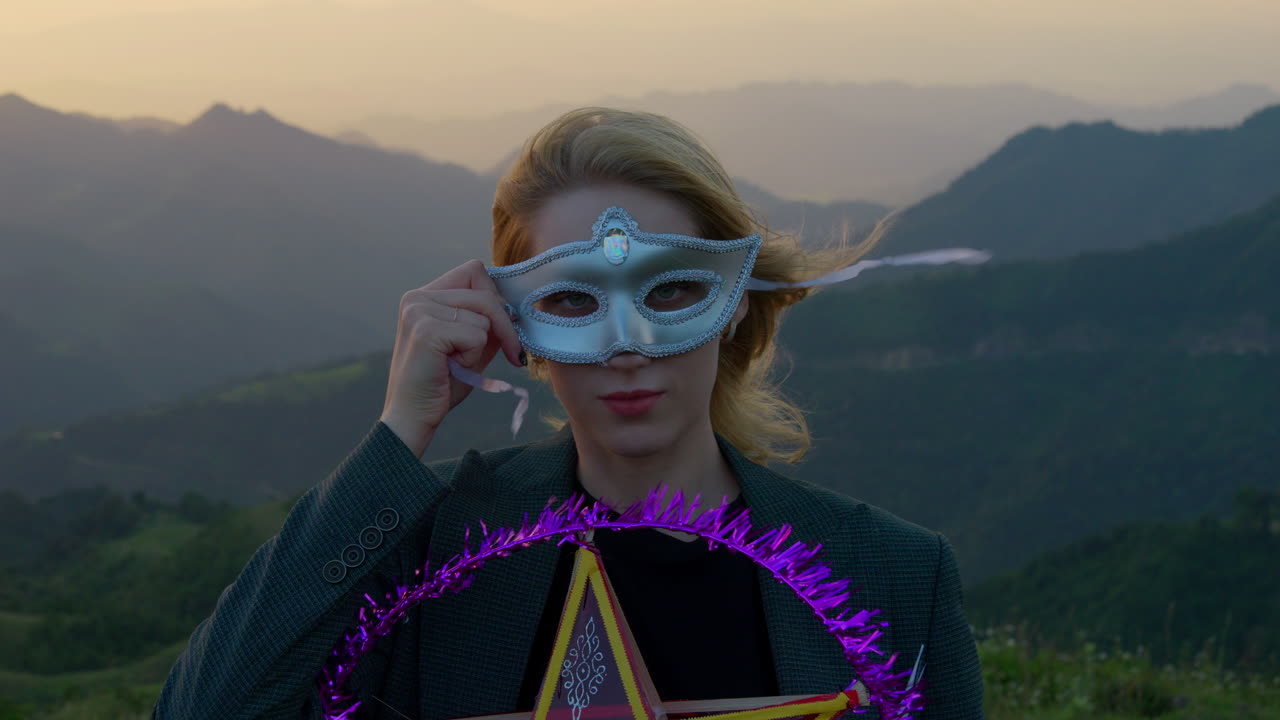 할로윈 정신에 그녀의 얼굴에 작은 마스크를 들고 있는 여자의 느린 동작