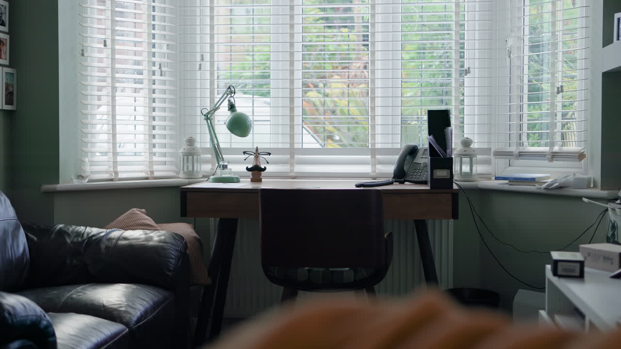 A desk in a living room with a window