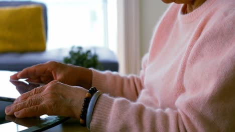 mujer mayor usando una tableta digital en la sala de estar