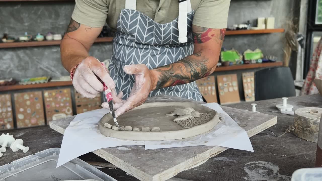 Craftsman Sculpting Clay with Tools in a Pottery Workshop