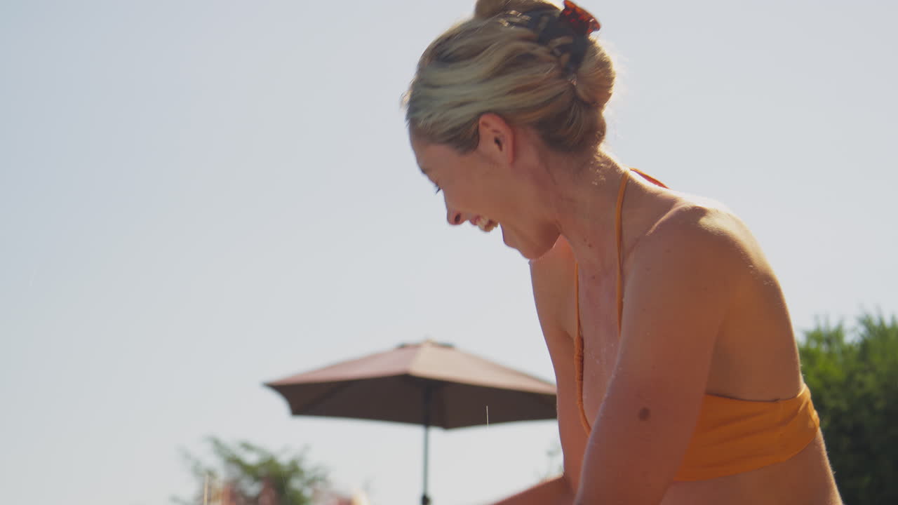 夏休みで笑顔の家族がプールで遊んで 母がスプラッシュしています