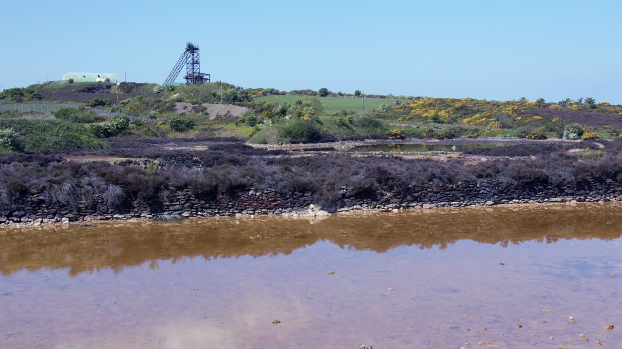 Wide shot of the sampling pool with headframe or headgear in background at mynydd parys mountain copper mine