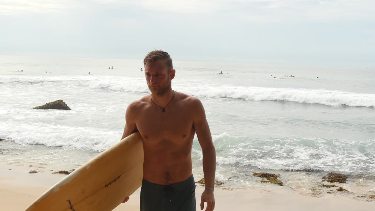 hombre regresando de una sesión de surf en una playa de arena tropical en sri lanka