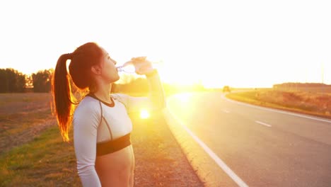woman taking a break and drinking water after running