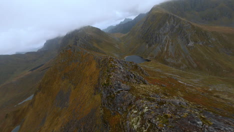 Drone-Fpv-Aéreo-De-La-Cresta-De-Una-Montaña,-Volando-A-Través-De-Las-Nubes,-Islas-Lofoten-En-Noruega,-Impresionante-Vuelo-Bajo