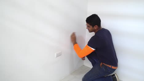 a man is wiping down the freshly painted interior wall of the house - static shot