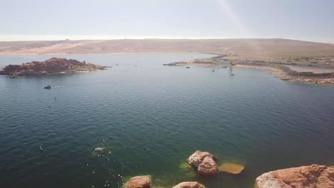 Una-Toma-Aérea-De-Una-Gran-Masa-De-Agua,-Un-Hermoso-Lago-En-El-Medio-Oeste-Con-Muchas-Rocas-Naranjas-Al-Mediodía