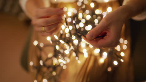 close-up of untangling christmas lights by woman in home comfort