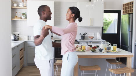 a diverse couple dances joyfully in bright kitchen