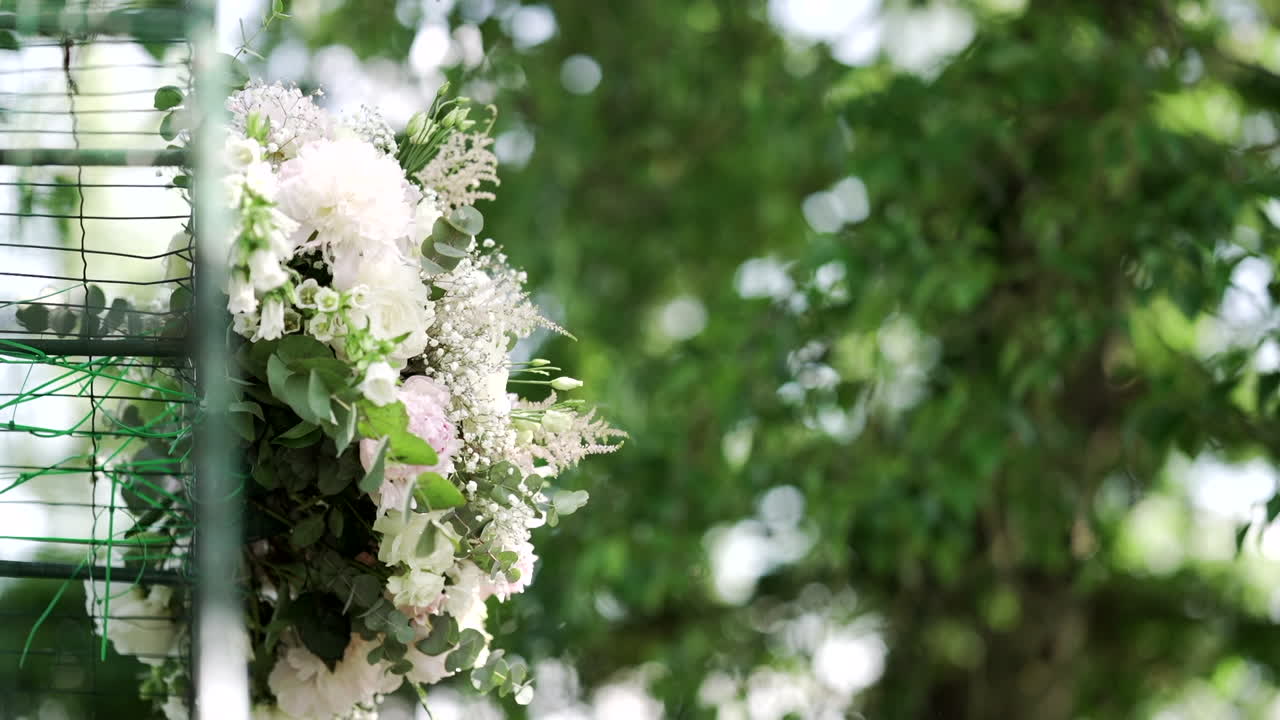 Beautiful floral arrangement with white and pink flowers, greenery in an outdoor setting