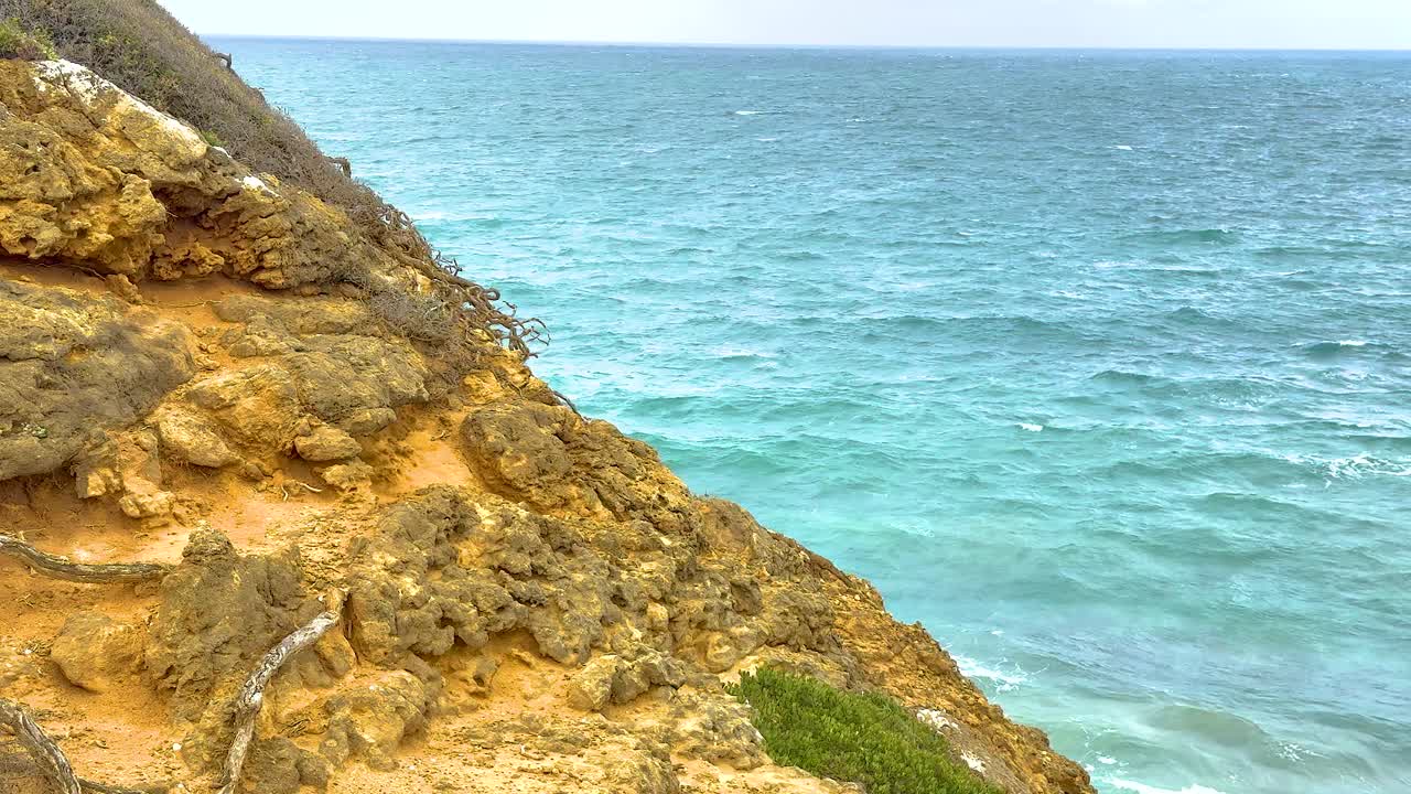 Una serena scena costiera con scogliere rocciose e oceano turchese sotto una luce diurna soffusa, catturata lungo la Great Ocean Road in Australia.