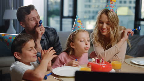 Mädchen-Bläst-Mit-Den-Eltern-Kerzen-Auf-Den-Kuchen.-Familie-Feiert-Geburtstag-Online.